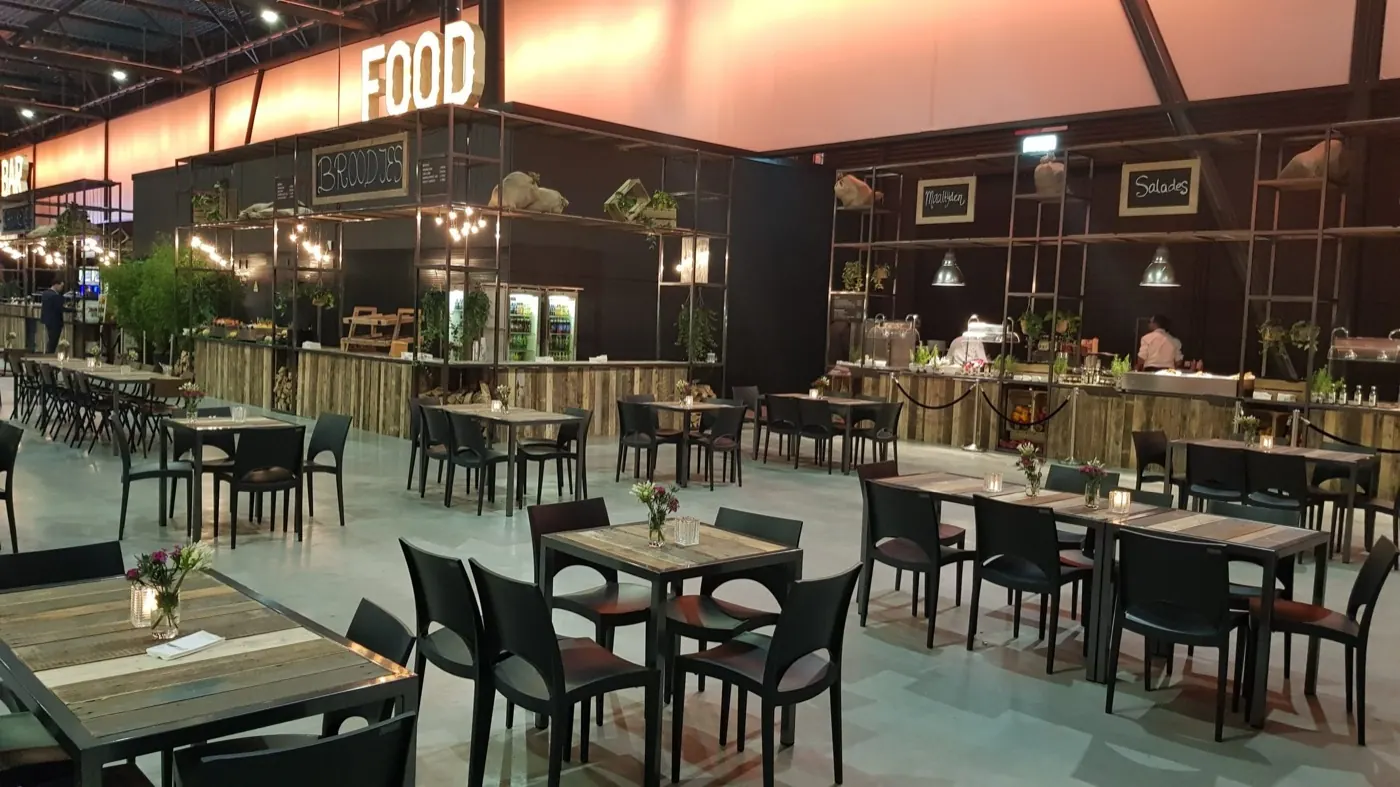 Opgebouwde evenementenhal met foodcorners, statafels en sfeerverlichting