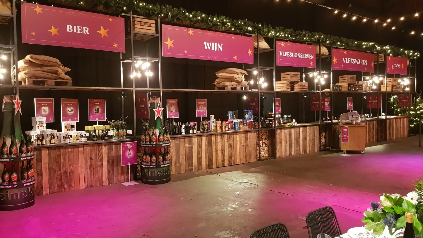 Kerstmarkt met marktkramen van steigerhout, roze bordjes en lichtsnoeren